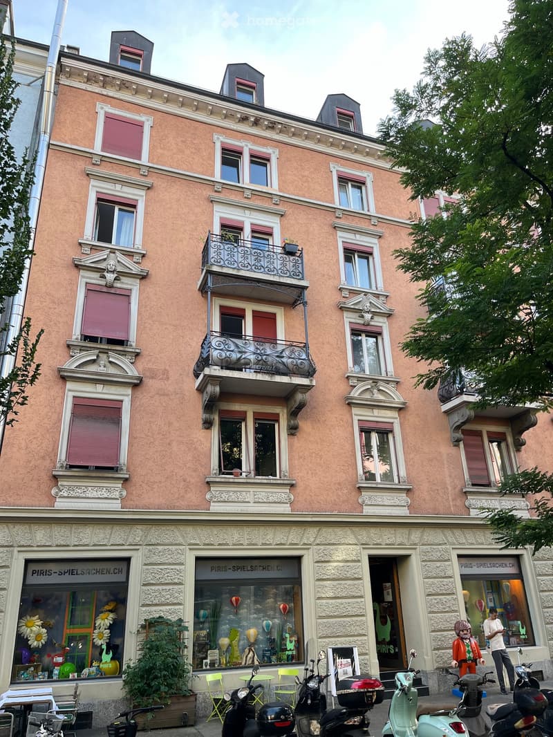 5-story pink building, white windows, 5 balconies, shops on ground floor
