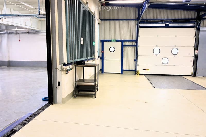 Industrial warehouse space with large double door, single door, and electrical outlet