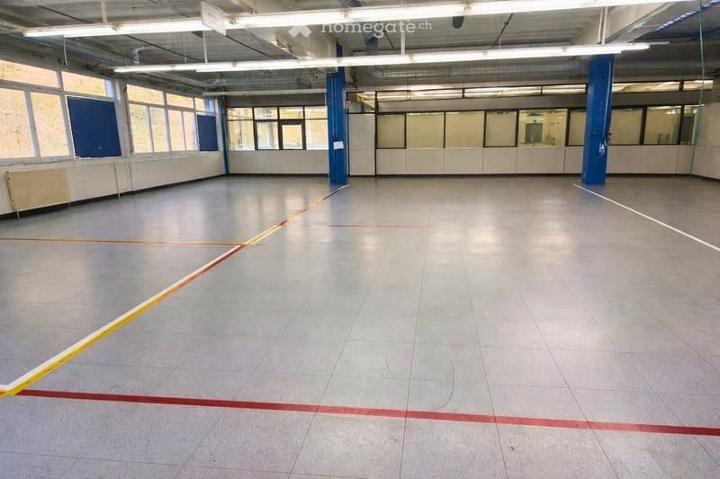 Empty room with tiled floor, metal poles, and fluorescent lights