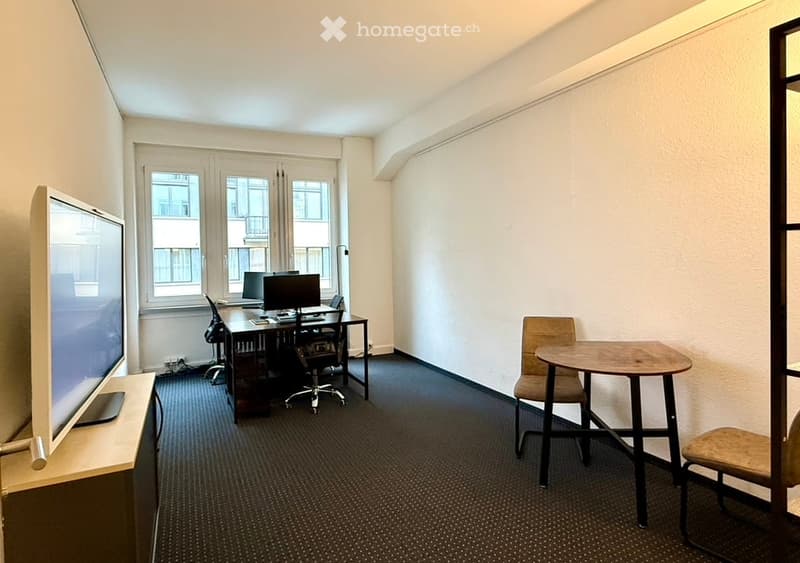Minimalistic office room with desks, monitors, and chairs. A television on a stand and a small table with another chair. White walls and black carpet. A window with a city view.