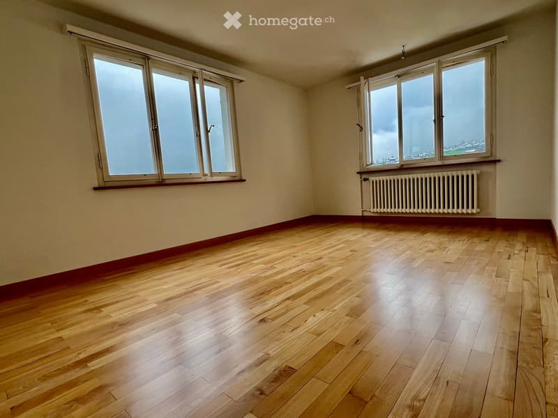 large room, white walls, windows, wooden floor, radiator