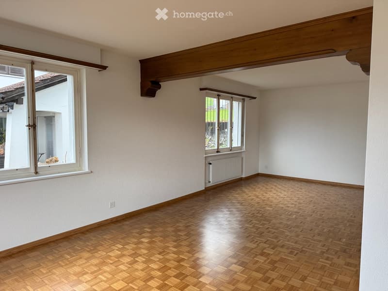 empty room with hardwood floors, large windows, wooden beam