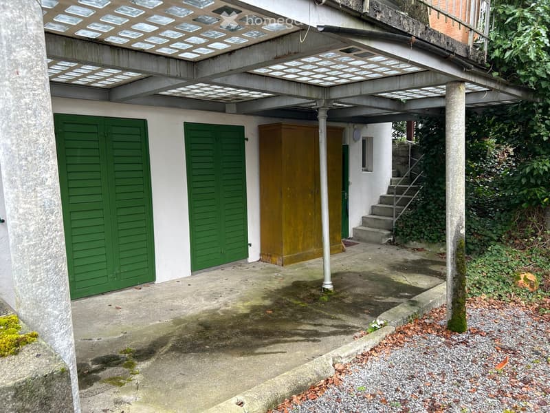 Concrete awning over garage, green shutters, wooden door, steps, green moss on columns