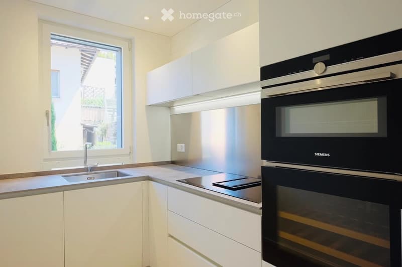 modern kitchen with white cabinets, silver countertops, stainless steel appliances including an oven and dishwasher, a sink, a window