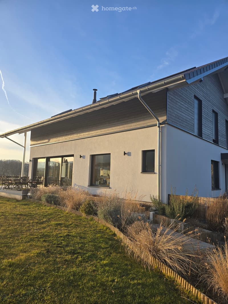 Detached modern house, double glazed windows, large glass doors, gray roof, terrace, wooden fencing, lawn