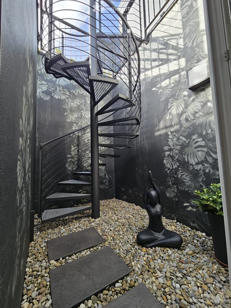spiral staircase, gravel pathway, a black statue, a green plant in a pot