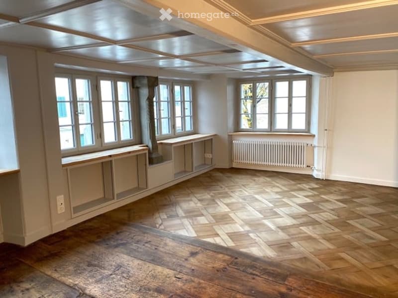 empty room, wooden parquet floor, large windows, built-in shelves, radiator