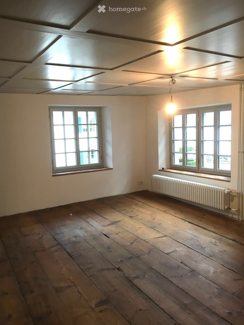 empty room, white walls, wooden floor, two windows, radiator