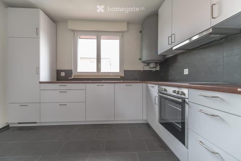 kitchen with white cabinetry, modern appliances, central window, tile flooring