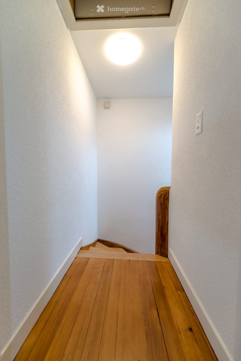 wooden floor, white walls, wooden railing, round light on ceiling