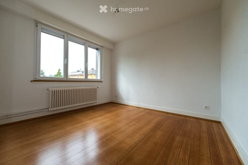 empty room, white walls, hardwood floor, large window, radiator
