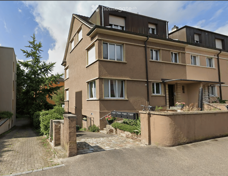 a 4-story brown apartment building, driveway with brick pavement, garden and plants on the front