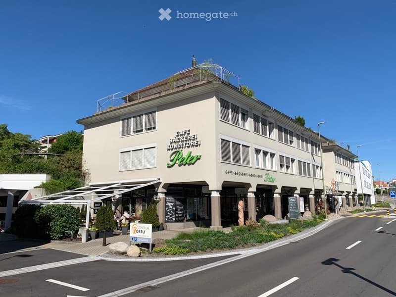A building with cafe and bakery on the ground floor, 4 story above with several windows and a small terrace on the top
