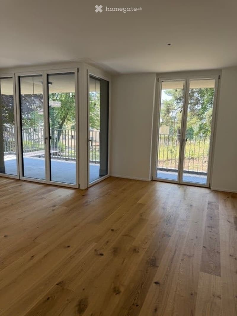 Empty room with light wooden flooring and large glass sliding doors leading to an outdoor area.