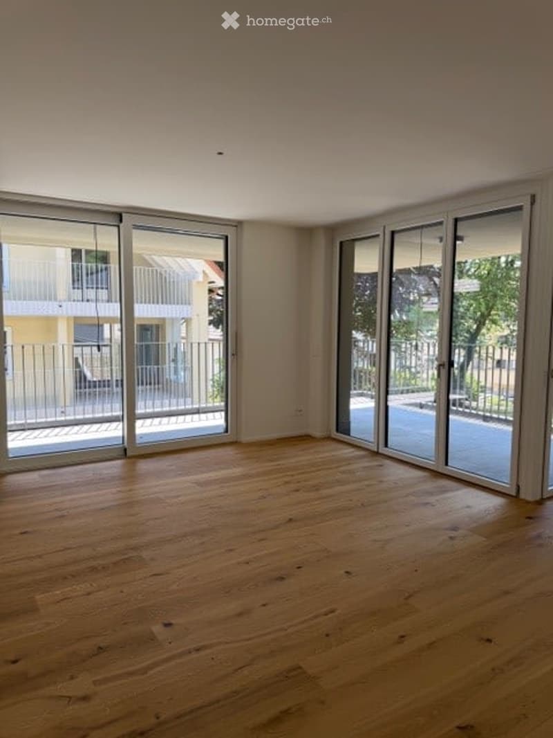 Empty room with wooden flooring and large sliding glass doors leading to a balcony.