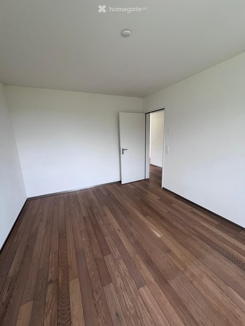 Empty room, hardwood floor, white walls, large open doorway, clean and minimal.