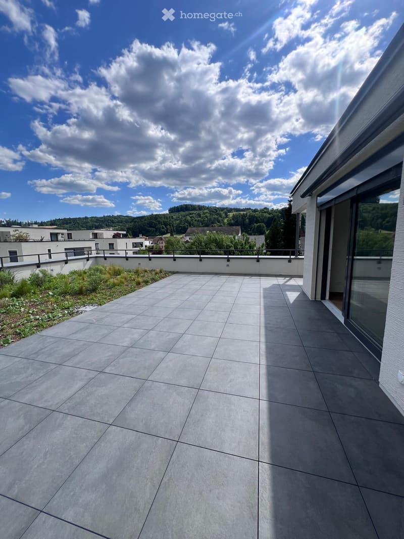 large tile terrace with railing, green plants, building views, mountain views