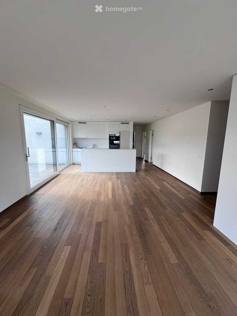 wooden floor, white walls, kitchen island, large sliding doors leading to a balcony