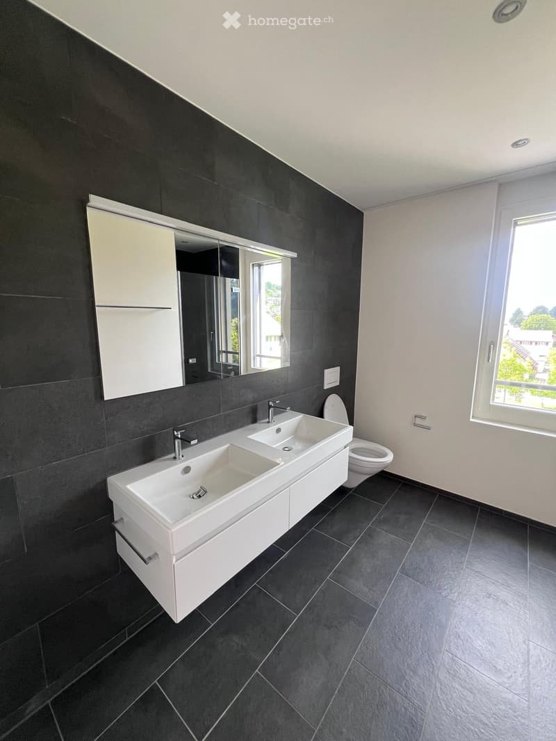 bathroom with two sinks, toilet, and a window with view