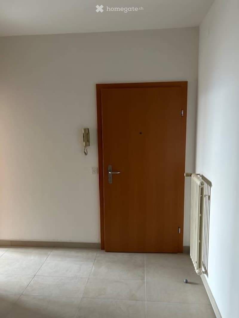 White walls, tiled floor, white radiator, door, telephone