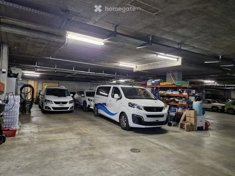 underground parking with several parked cars and a lot of storage space