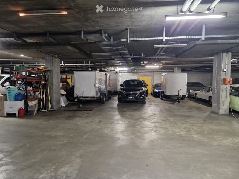 underground garage with vehicles parked and an aisle