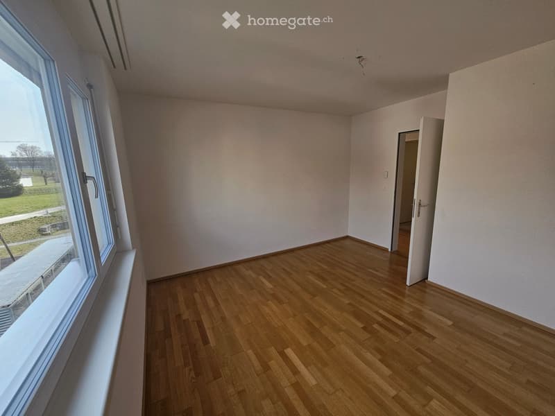 Empty room, white walls, wooden floors, large window with a view
