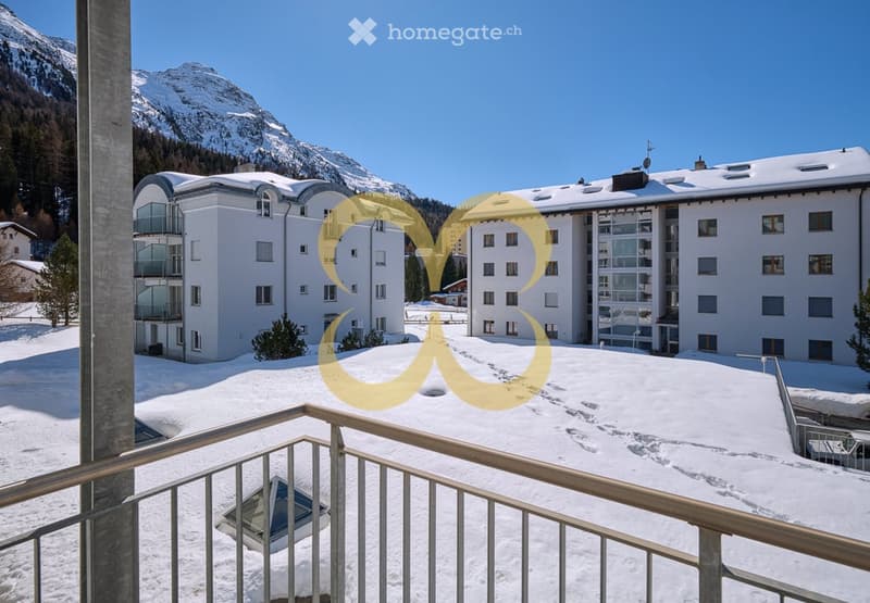 Large building with balcony, snow cover, mountains in the background