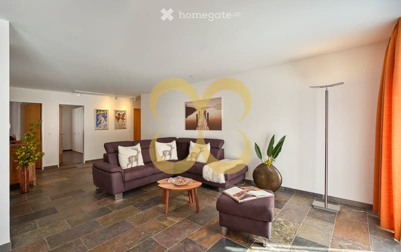 L-shaped couch, coffee table, ottoman, floor lamp, plants, tiled floor, paintings on wall