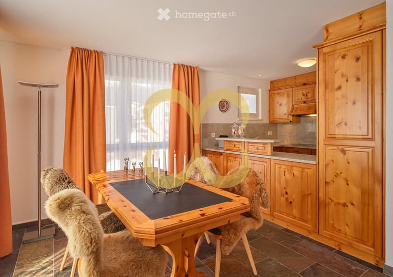 Dining area with wooden table and fur chairs, wooden cabinets and counter with stools, floor lamp, wooden ceiling, and curtains
