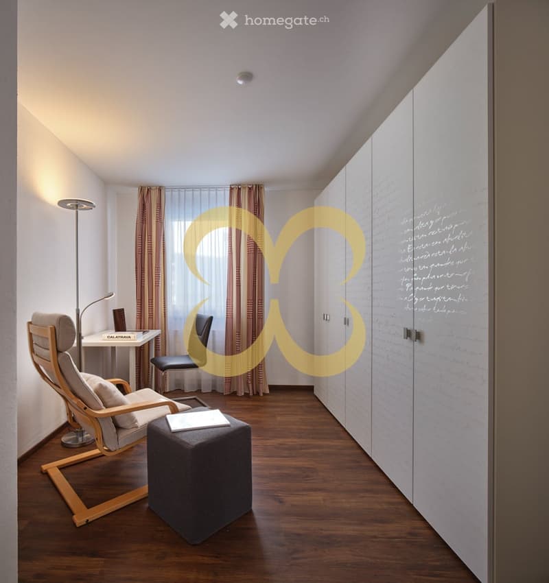minimalist room with hardwood floors, two armchairs, a desk, storage cabinets