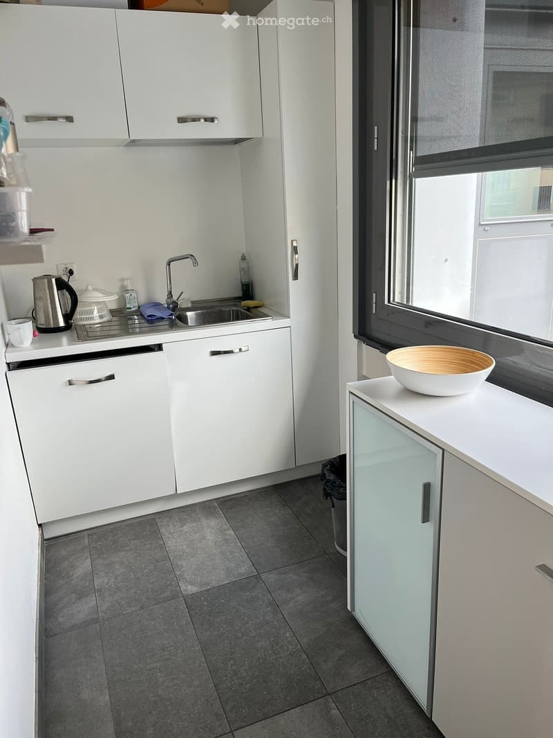 small kitchen with sink, cabinets, window, and tiled floor