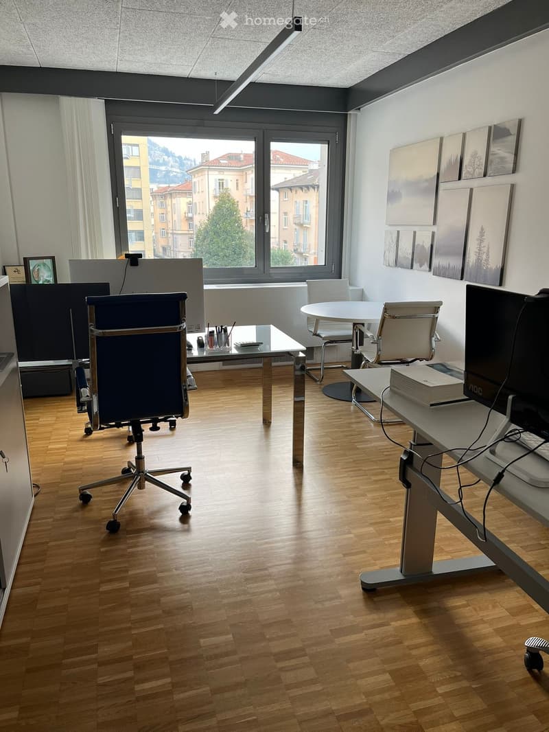 open space office room, wooden floor, large windows, office chairs, tables, monitors, shelves