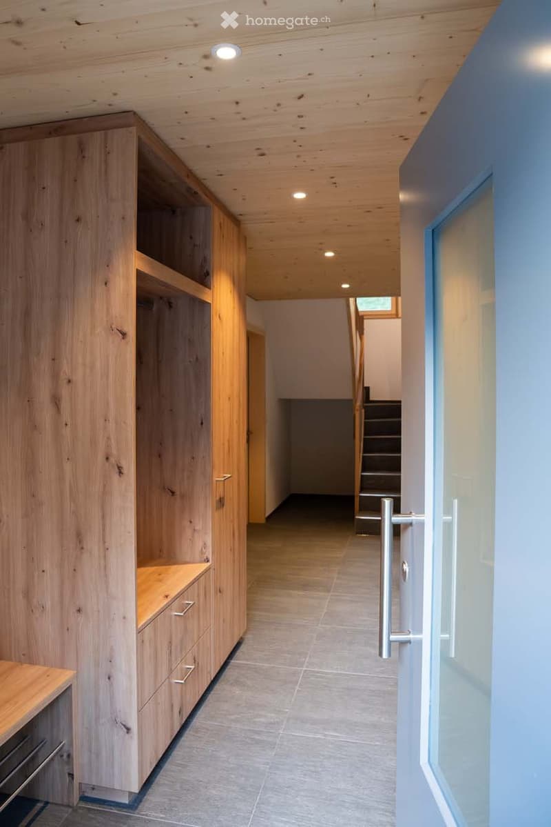 large wooden wardrobe with drawers, tiled floor, stairs leading up, a door on the right