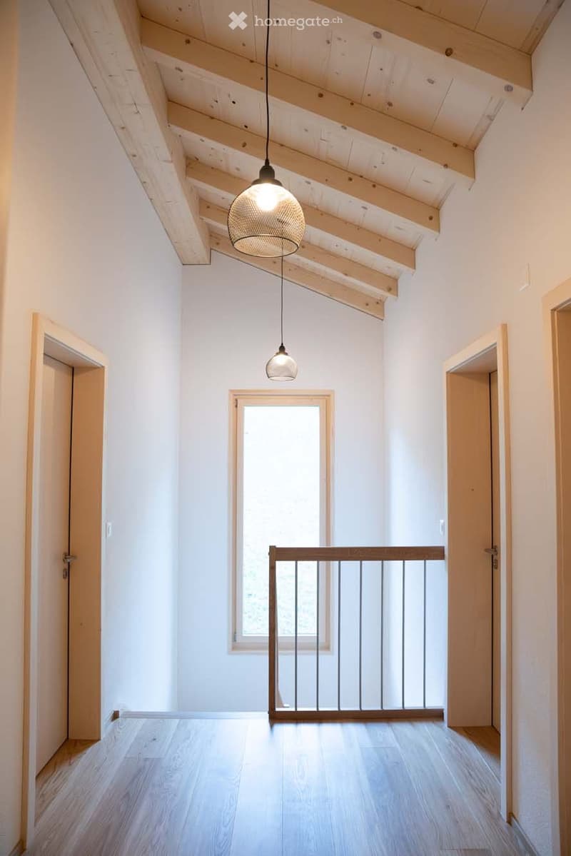 empty corridor with wooden floor, white walls, wooden exposed ceiling, glass window, and metal railing