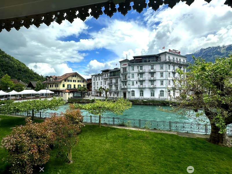 House beside a river, with a fence, mountains in the background, yellow house