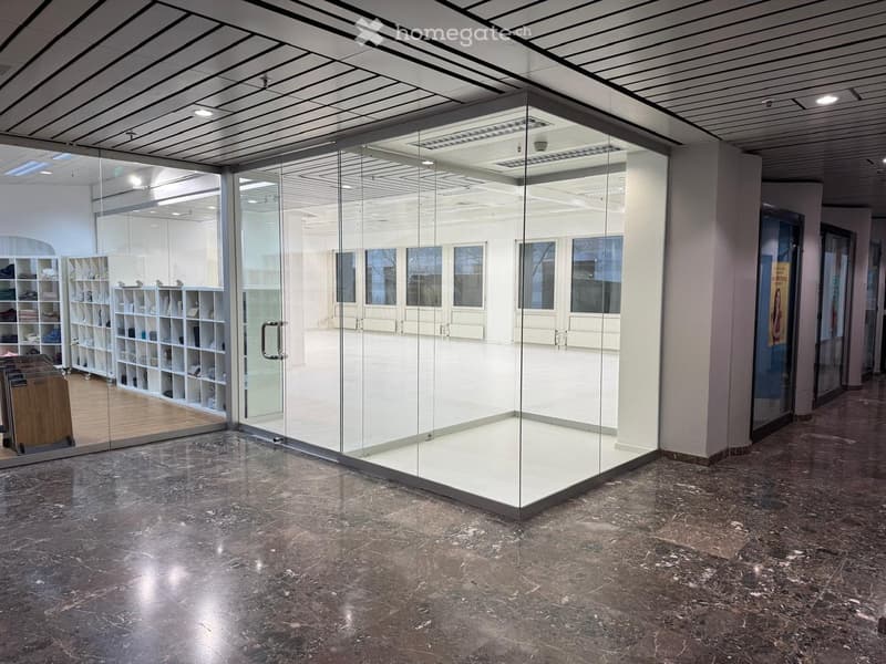 an empty room with marble flooring, glass walls, and ceiling with panels and lights