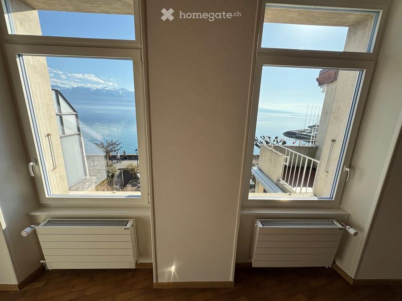 large windows with balcony, wooden floor, white radiators, scenic view of the sea and mountains