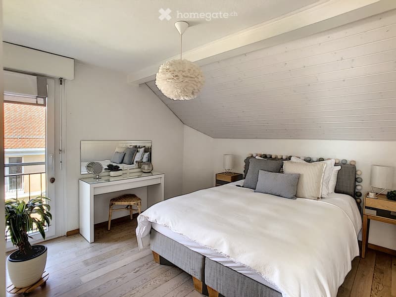 bedroom with bed, two nightstands, nightstand lamp, large mirror, stool, and potted plant