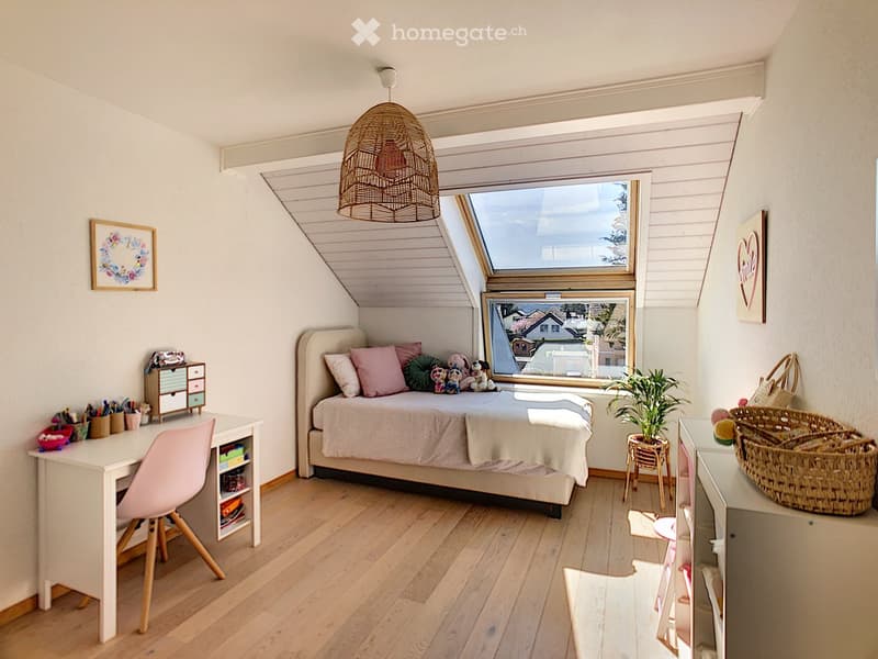 small bedroom with wooden floor, white walls, single bed, desk, chair, bed headboard with pillows, ceiling lamp, skylight, storage boxes, stuffed animals, basket, plant, baskets and handbag, framed picture on the wall