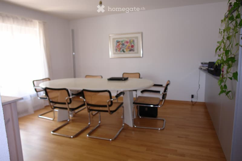modern dining table, modern chairs, large window with white curtains, a picture frame on the wall, electronic devices on a shelf, wooden floor