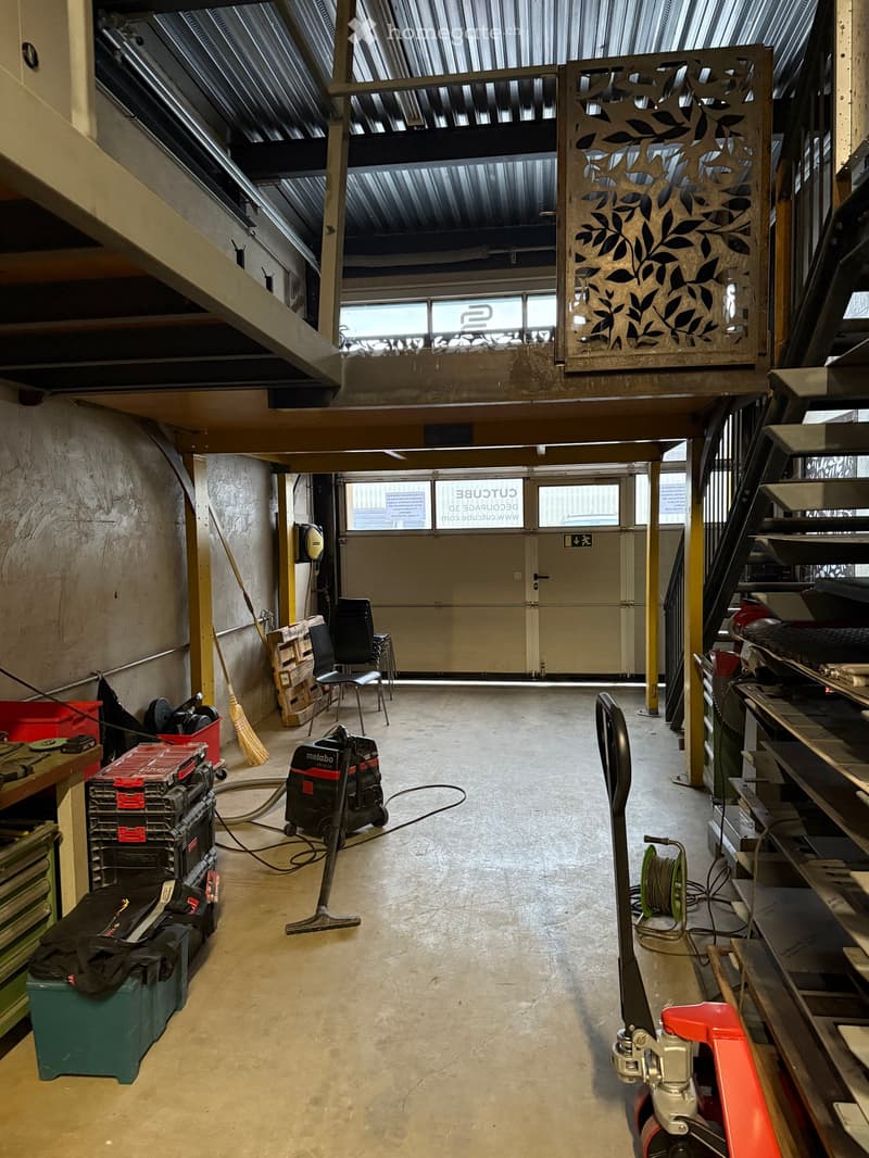 Warehouse with double garage doors, elevated walkway, storage racks, cleaning equipment