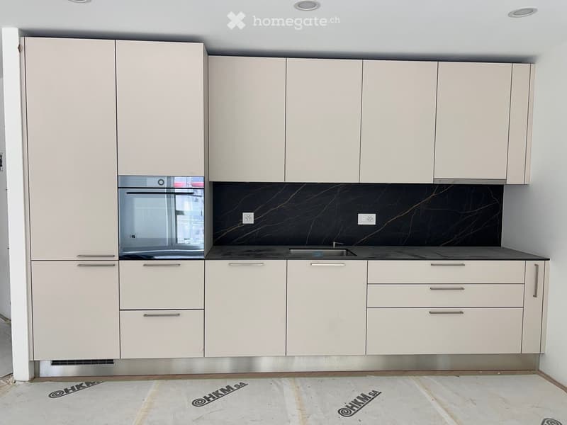 modern kitchen with white cabinets, black marble countertop, stainless steel sink, built-in oven, power outlets