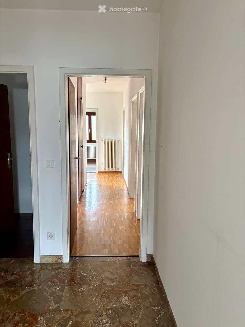 Marble floor, wooden floor in the hallway, white walls, radiators, an open door, an open window.