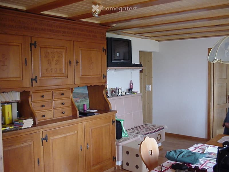 wooden cabinets, TV mounted on wall, dining table with chair, books on cabinet