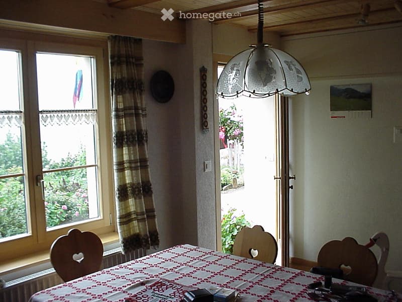 Dining room with a table and chairs, a window with curtains, a wall with a painting and picture frame, a wooden ceiling, a glass door leading to a patio