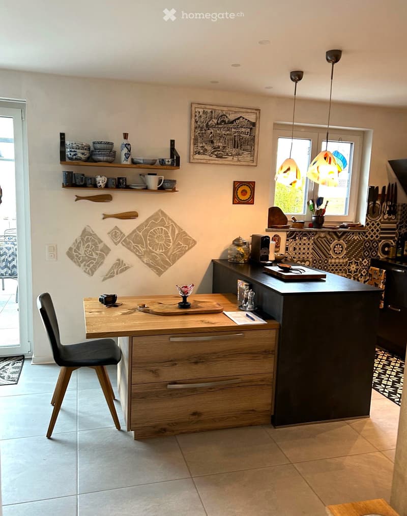 kitchen, dining area, tiled flooring, wooden counter, shelves, island with sink and coffee machine, black tiled wall, window