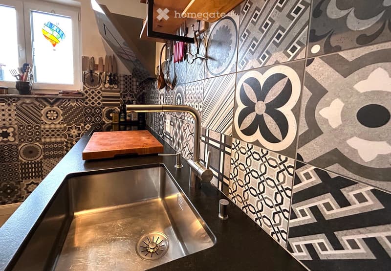 Countertops, stainless steel sink, modern faucet, patterned tiles, overhead kitchen shelves, hanging utensils, wooden chopping board, countertop space, stainless steel faucet.