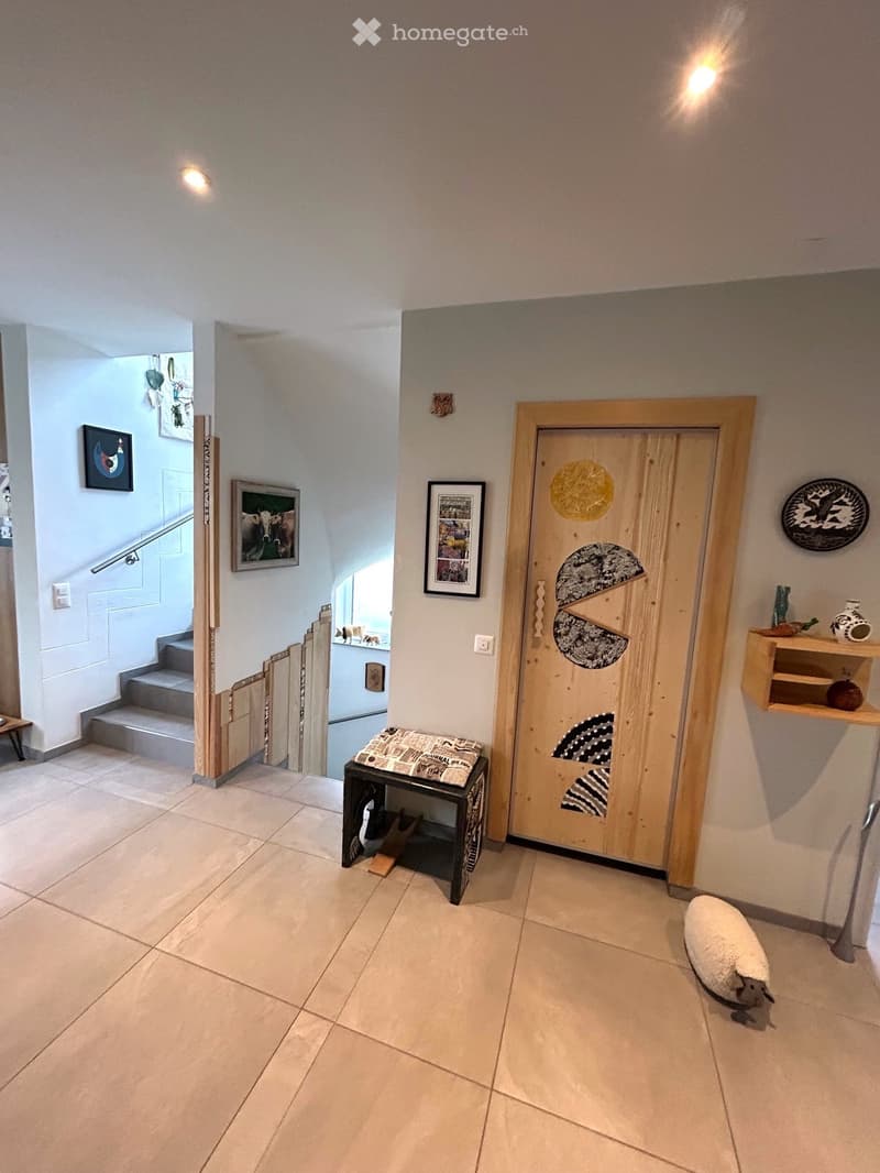 large tile floor, wall mounted picture frames, wood table with newspaper, wood door, wooden staircase