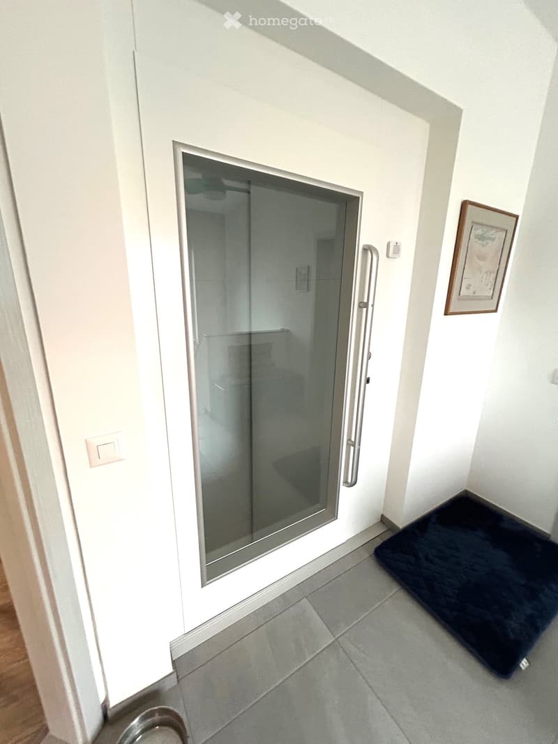 Entrance with a sliding glass door and a black mat on the tiled floor.